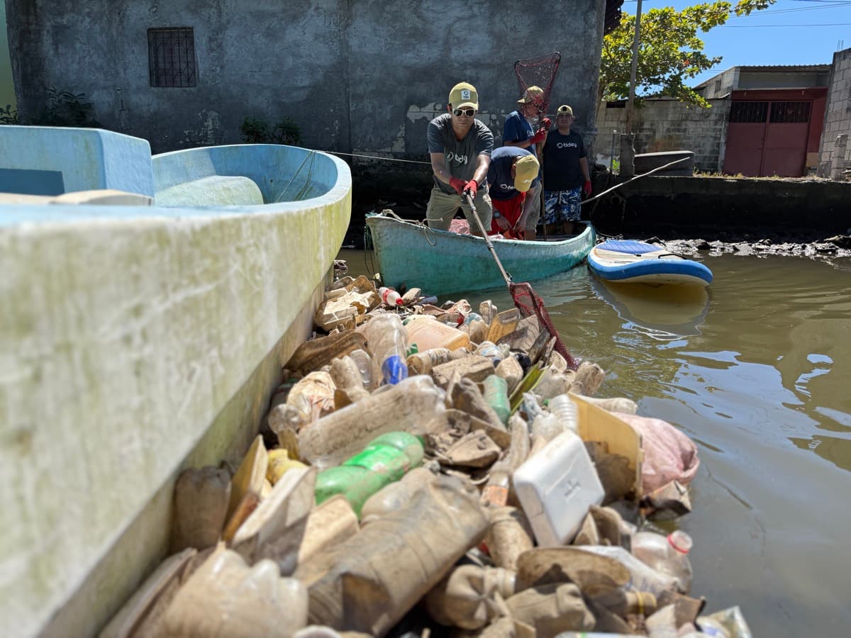 Tidey Ocean workers collecting plastic waste from a polluted waterway by boat
