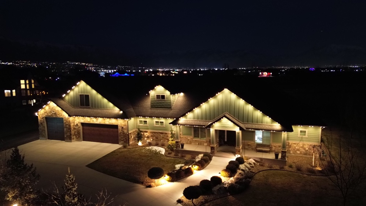 Soft warm white mood lighting along the roofline and landscape of a luxury home on the Wasatch Front at dusk