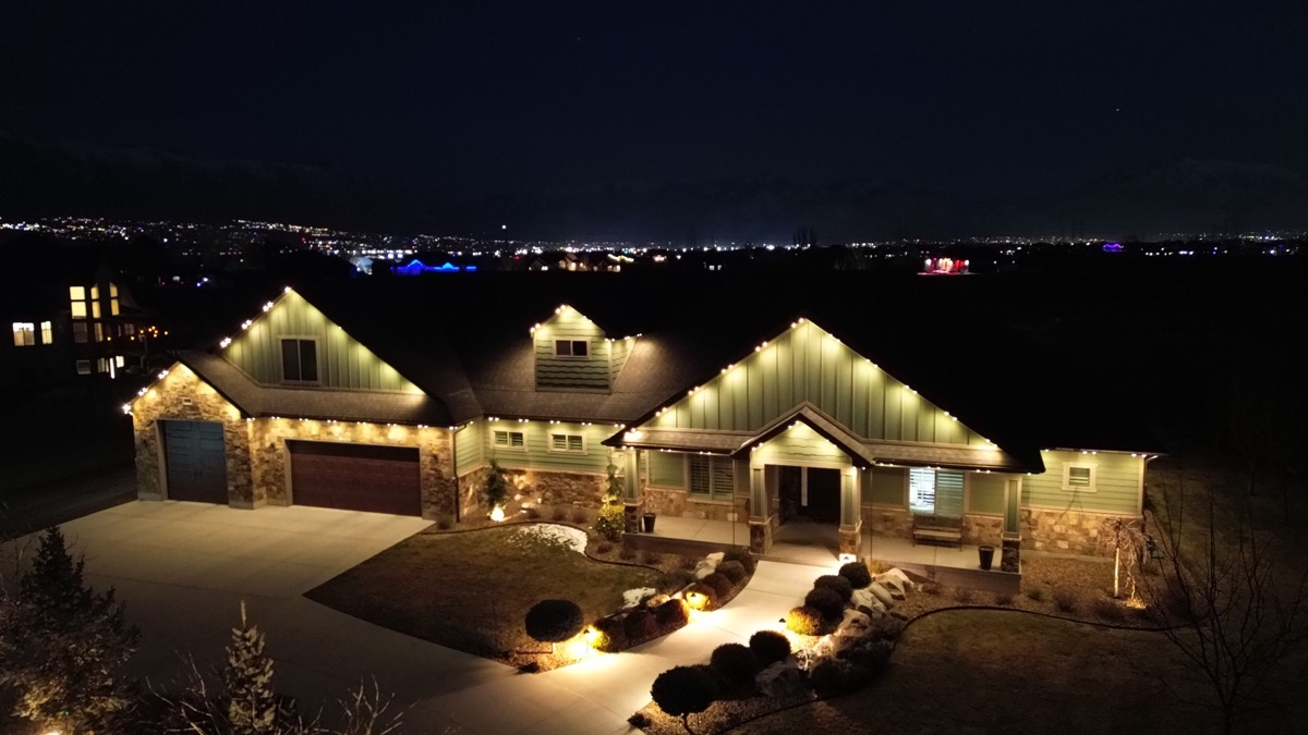 Drone view of TruLight RGBW warm white permanent lighting on a large Wasatch Front home at night